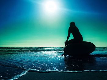 Silhouette man by sea against sky