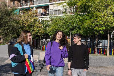 Young diverse friends walking on the street with the lgbt rainbow flag.