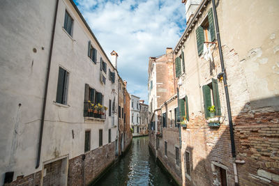 Canal amidst buildings against sky in city