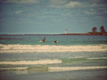 People enjoying at beach against sky