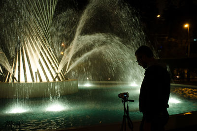 Rear view of woman photographing illuminated at night