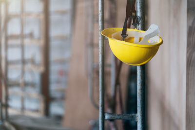 Close-up of yellow window hanging on metal fence