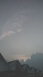 Houses and silhouette mountains against sky during sunset