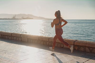 Full length of woman standing on railing against sea