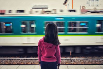 Rear view of woman standing on train at railroad station