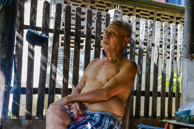 Shirtless senior man sitting indoors