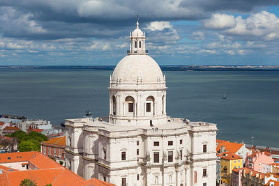 View of buildings and sea against cloudy sky