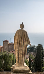 Statue by tree against clear sky