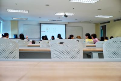 Empty chairs with students in background in the seminar and education concept