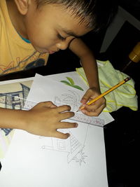 High angle view of boy drawing on paper