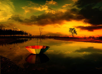 Abandoned umbrella in lake against sky during sunset