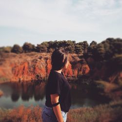 Rear view of woman standing on rock against sky