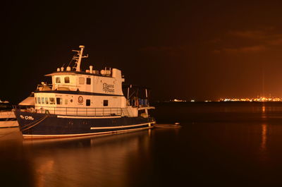 Boats moored in illuminated city at night