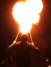 Rear view of man with fire crackers at night