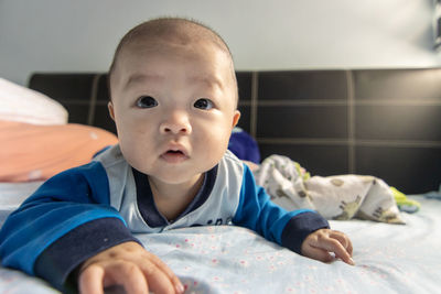 Portrait of cute baby lying on bed at home