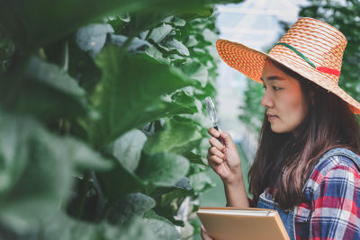 Woman standing by plants at greenhouse