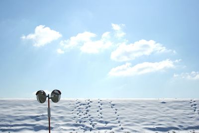 Traffic mirror on snow covered field against sky