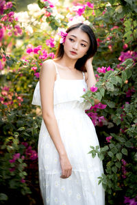 Portrait of a beautiful young woman standing by flower