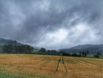 Scenic view of field against cloudy sky