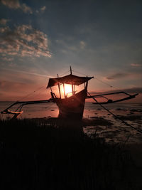 Silhouette ship moored in sea against sky during sunset