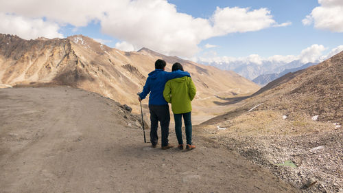 Rear view of man standing on mountain against sky