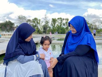 Rear view of mother and daughter sitting outdoors