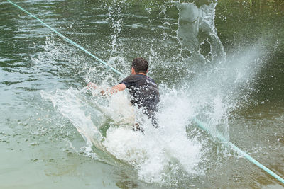 Rear view of man surfing in water