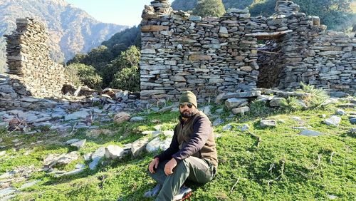 Full length of man sitting on rock