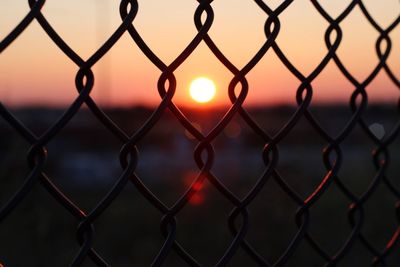 Full frame shot of chainlink fence against sky during sunset