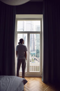 Side view of young man looking through window