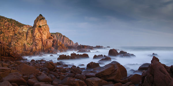 Rock formations in sea against sky