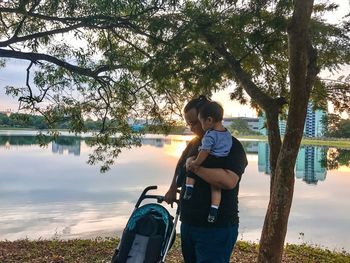 Boy standing by lake against sky