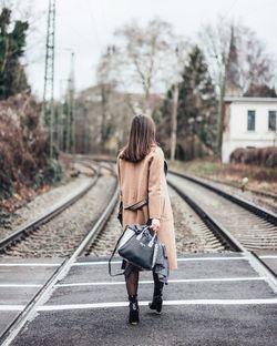 Rear view of woman walking on railway tracks