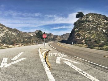 Road sign by mountains against sky