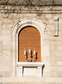 Three candlestick in front of a window with closed window shutters