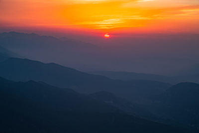 Scenic view of silhouette mountains against romantic sky at sunset