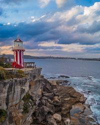 Lighthouse on beach by sea against sky