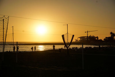 Silhouette people on beach against clear sky during sunset