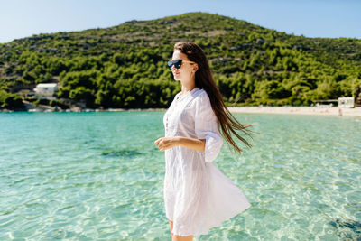 Portrait of smiling young woman standing against sea