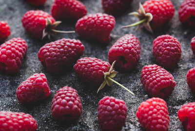 Raspberries food background - ripe harvested raspberry arranged on gray stone texture