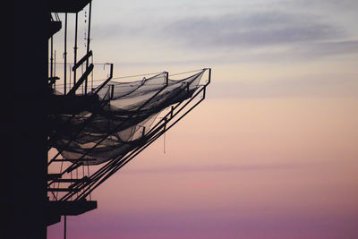 Low angle view of silhouette crane against sky at sunset