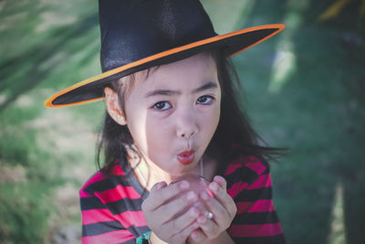 Portrait of girl wearing witch hat holding crystal ball