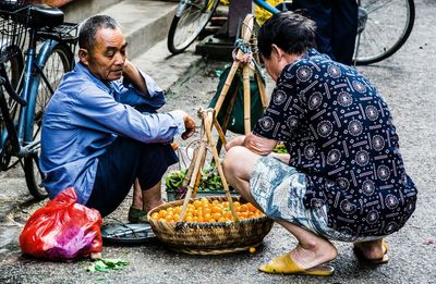 Rear view of men buying tomatoes from vendor at street market