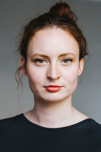 Close-up portrait of young woman against gray background