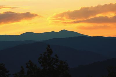 Scenic view of silhouette mountains against orange sky