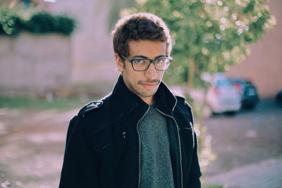 Portrait of young man standing on footpath