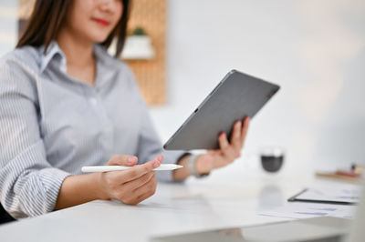 Midsection of woman using mobile phone on table