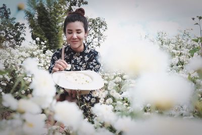 Midsection of woman plucking flowers