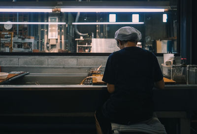 Rear view of woman cooking food in commercial kitchen