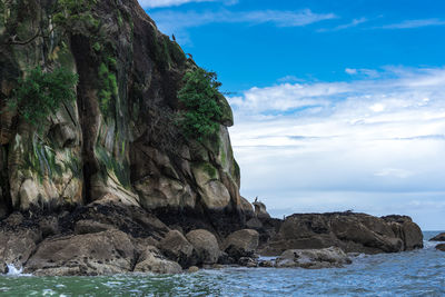 Rock formation in sea against sky